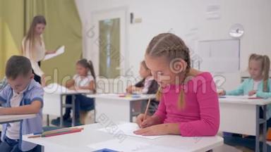 小女生在灯光教室里画画的肖像，坐在同学和年轻的背景下的课桌后面